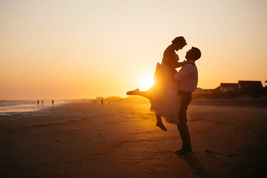 Wedding couple hugs on beach at sunset
