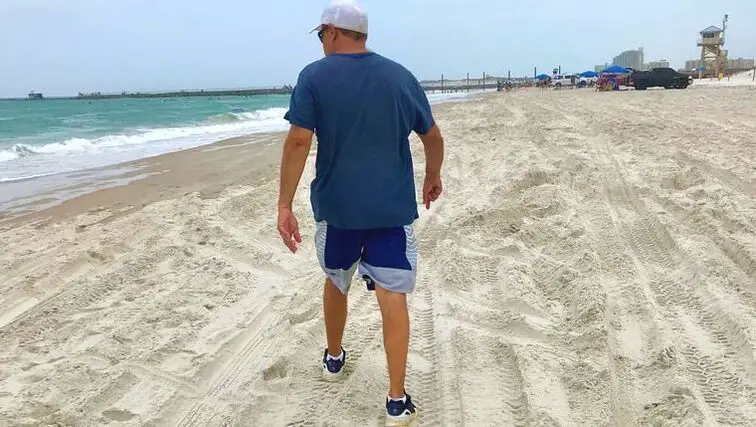 Man walks through sand on Ponce Inlet Beach