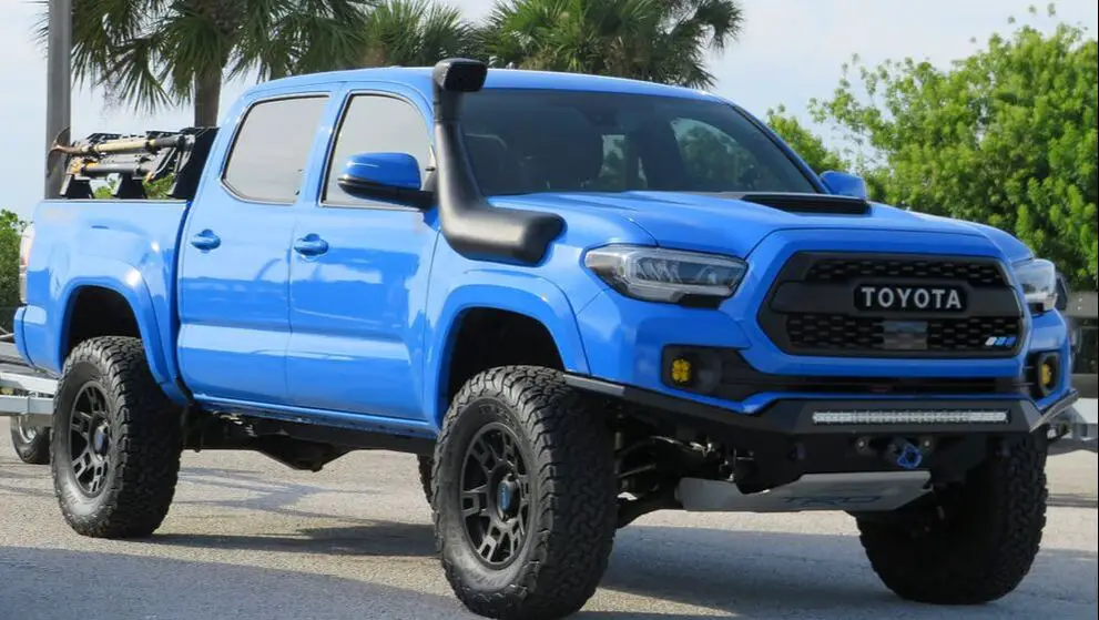 Blue Toyota Tacoma pickup truck in beach parking lot