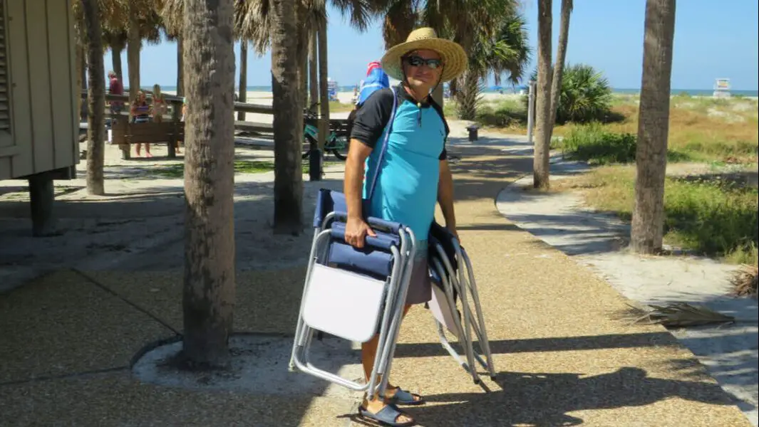 Man carries beach chairs in Sand Key Park