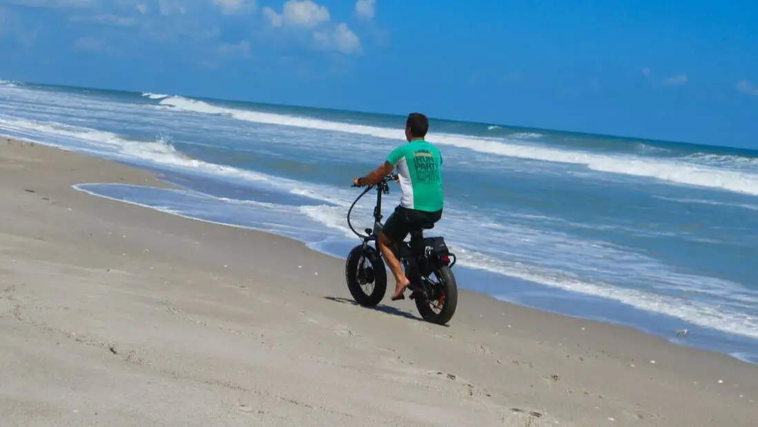 Man rides bike on Pelican Beach FL