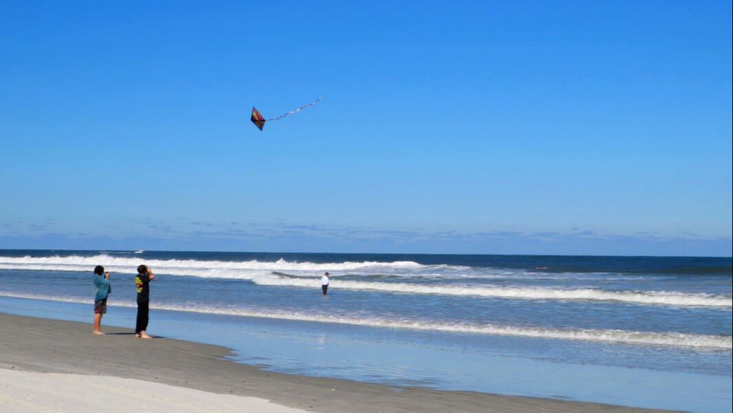 People flying kite on New Smyrna Beach